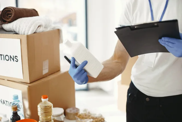 Focused volunteer in gloves sorting donation supplies in a community center. Handling in-kind support as a documented sponsorship