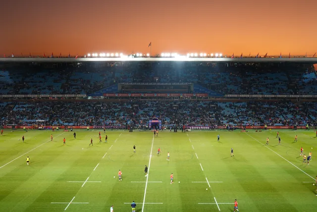 Exciting rugby game unfolding under stunning sunset in large stadium. Splitting budget between rights and audience activity