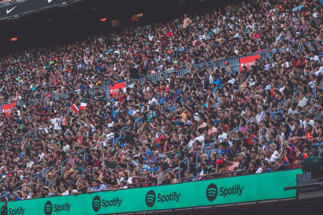 A packed stadium with enthusiastic fans cheering, showcasing diverse spectators. Sponsorship research and audience evidence