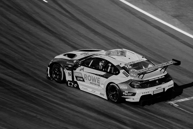 A dynamic black and white photo of a high-speed race car on a track, capturing motion and speed. Sponsorship strategy for brands
